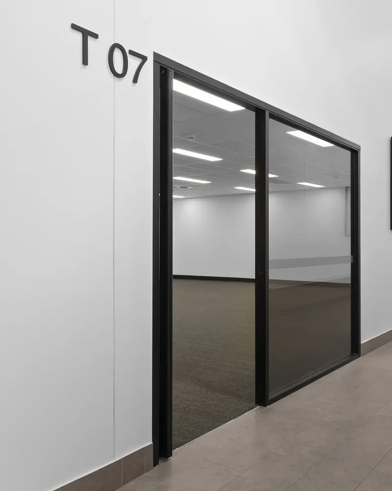 Tenancy 7's glass double doors off a tiled corridor, with the empty suite visible inside
