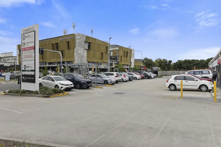 Caboolture Hospital's building, with its name on the facade, seen across McKean Street from the Hub's car park