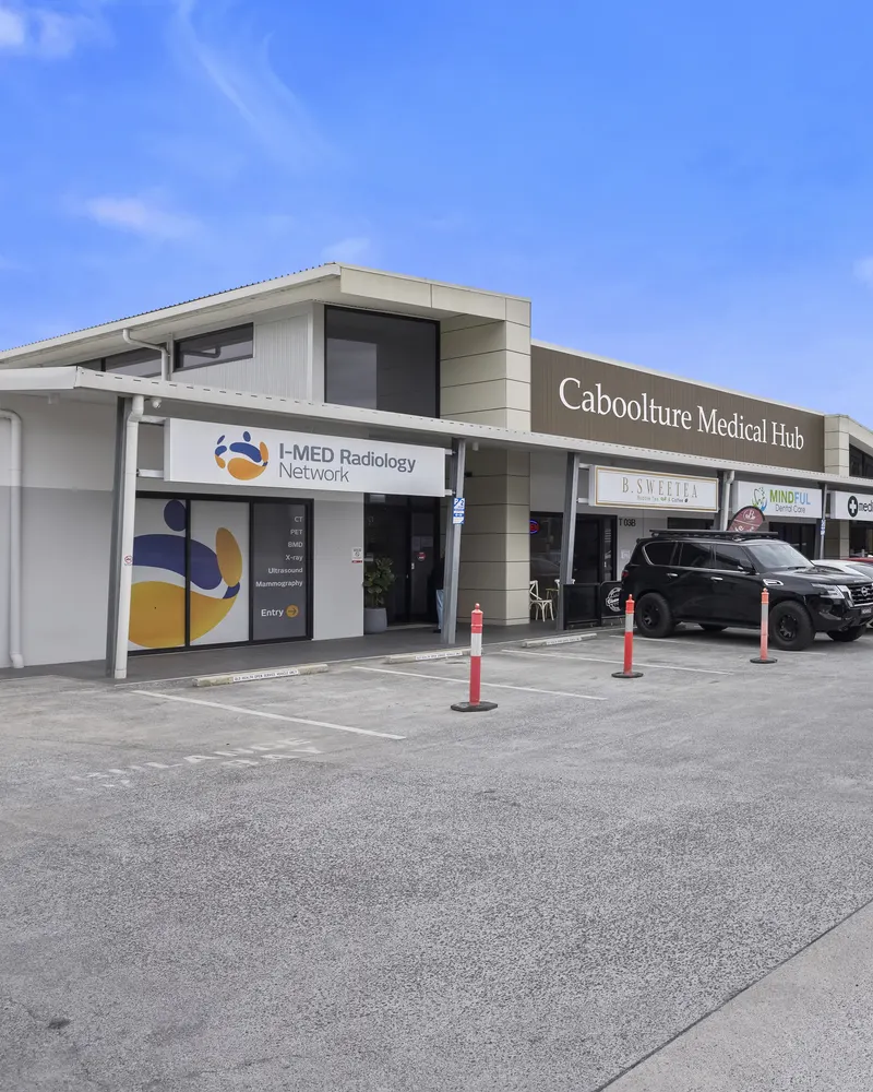 The frontage of Caboolture Medical Hub: a single-level building with the centre's name on a timber-look panel, I-MED Radiology at one end, a covered walkway and on-site parking in front
